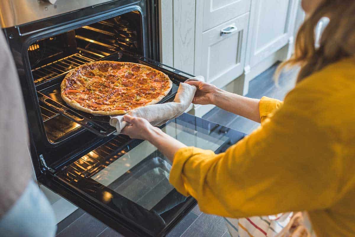 taking a pizza out of the oven