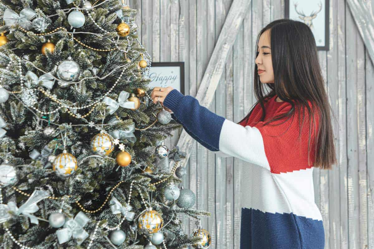 Young lady decorating a tall christmas tree