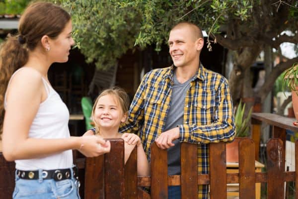 Smiling neighbors talking at backyard garden